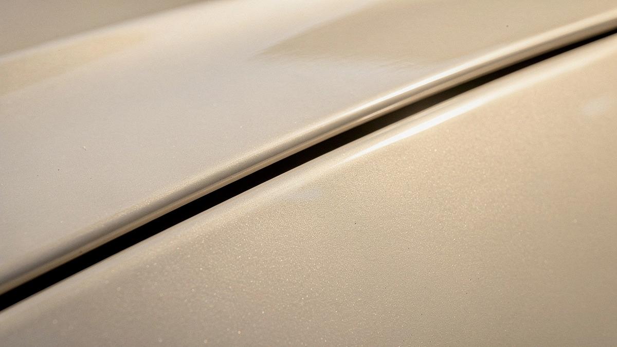 Macro close-up of a painted automotive panel edge catching warm light